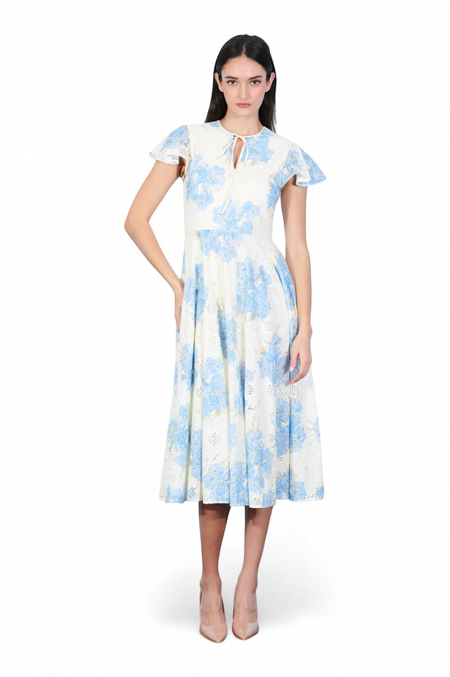 MSA Haute Couture white midi dress with blue floral print and eyelet details, featuring flutter sleeves and a tie neckline.