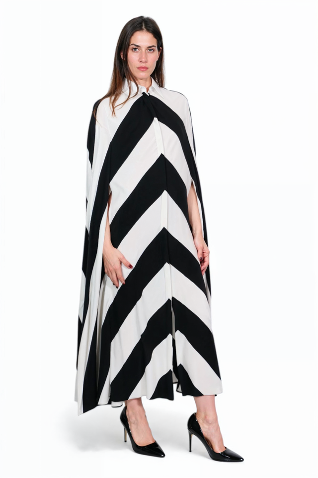 Valentino chevron cape dress on model, three-quarter view — collared cape with arm slits.
