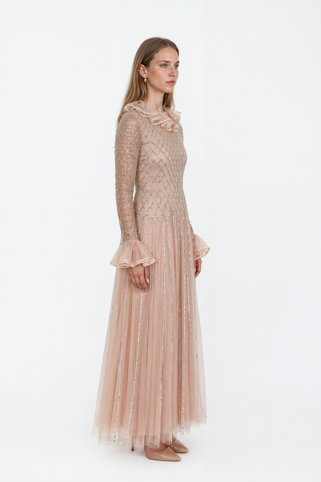Side view of a Valentino champagne beaded tulle gown with flared organza cuffs and pleated skirt